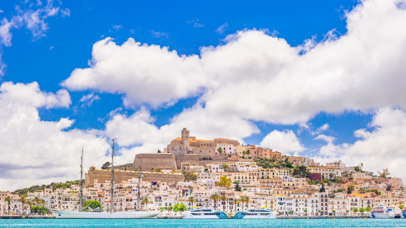 An extremely detailed view of Eivissa's old town centre and marina, bright sky, picturesque clouds, a moored sailing ship, the iconic skyline of Dalt Vila dominated by the cathedral church of Santa Maria de les Neus. Developed from RAW.