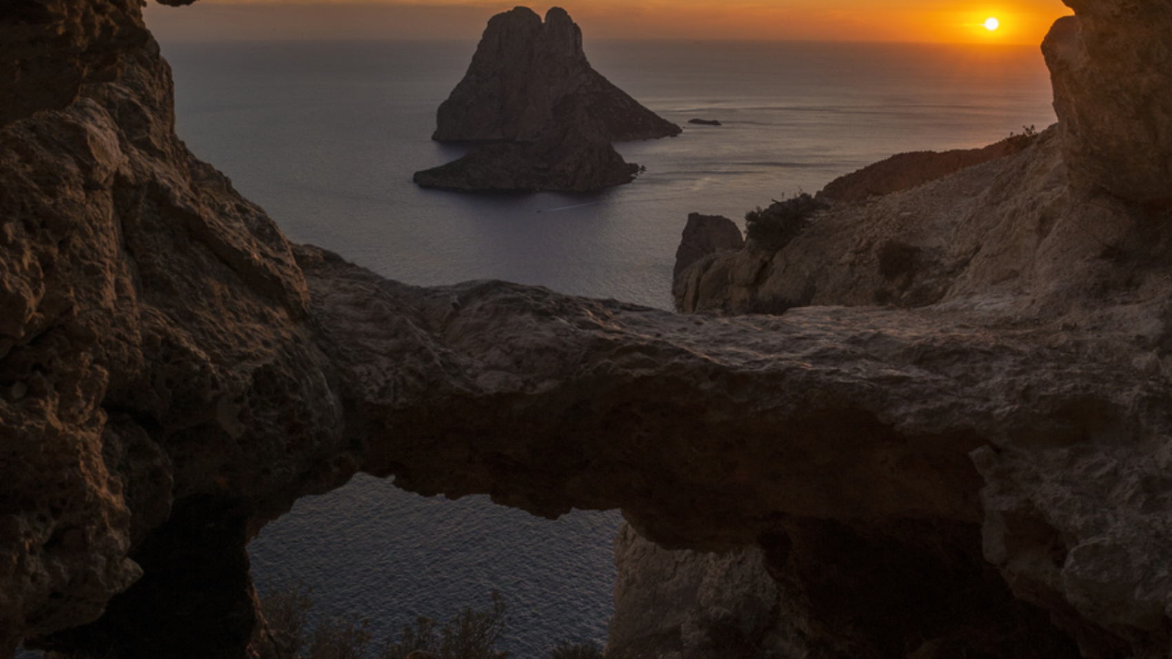 Es Vedra islet view through the rock holes of a cave at sunset, Sant Josep de Sa Talaia, Ibiza, Balearic Islands, Spain